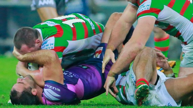 MELBOURNE, AUSTRALIA - MAY 16:  Cameron Smith of the Storm kicks Issac Luke of the Rabbitohs whilst being tackled during the round 10 NRL match between the Melbourne Storm and the South Sydney Rabbitohs at AAMI Park on May 16, 2015 in Melbourne, Australia.  (Photo by Scott Barbour/Getty Images)