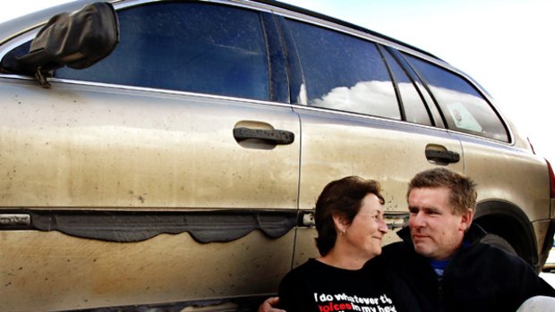 Kinglake residents Lois McDonald and Luke Vandenberk rest beside the vehicle they used to drive to the CFA building once the firestorm had passed.