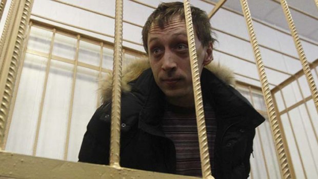 Behind bars: Pavel Dmitrichenko looks out from the defendant's holding cell during a court hearing.