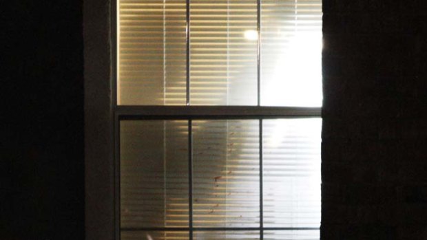 A crime scene photographer is silhouetted against blood splattered window blinds in an apartment where seven people were shot and killed on Christmas day in Grapevine, Texas.