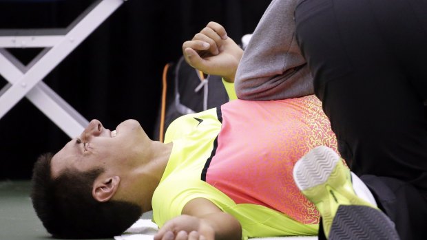 Bernard Tomic, of Australia, grimaces as he gets treatment from trainer Clay Sniteman.