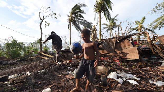 Grim aftermath: A child walks through the ruins of his family home with his father Phillip, on March 16 in Port Vila and, below, more scenes of the devastation in Vanuatu. 