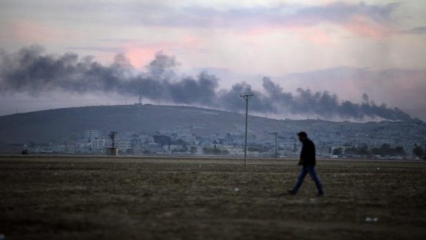 Hanging reminder: Smoke from a fire caused by a strike rises over Kobane.