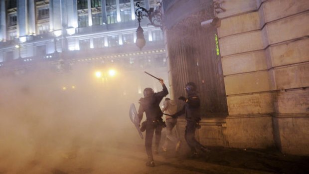 Batons ready ... two riot police chase a protester during clashes near the parliament in Madrid during a general strike on Wednesday.
