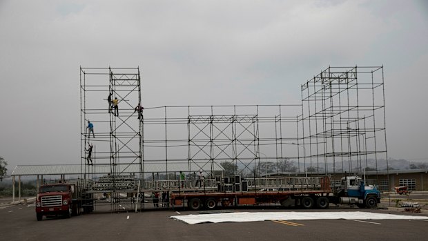 Workers build a stage for the upcoming pro-government concert coined "Hands Off Venezuela" on the Venezuelan side of Tienditas International Bridge that leads to Colombia.