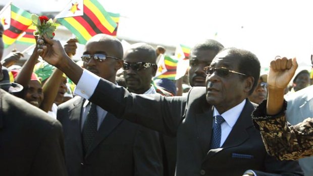 Waving flags, supporters greet Zimbabwean President Robert Mugabe upon his arrival at Harare Airport.