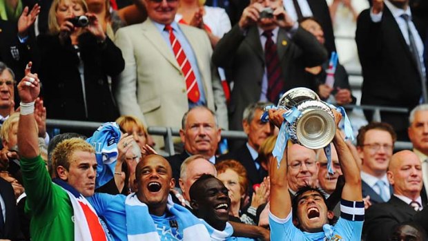 Manchester City skipper Carlos Tevez hoists the trophy aloft.