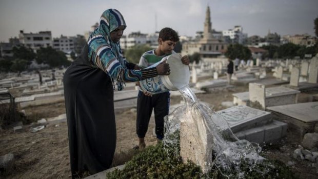 During a lull in fighting, a Palestinian woman washes the grave of a relative at Sheikh Radwan cemetery, northwest of Gaza City on the first day of Eid al-Fitr holiday, which marks the end of Ramadan.