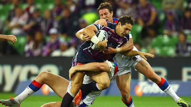 Billy Slater of the Storm is tackled by Chris Houston and Kurt Gidley of the Knights.