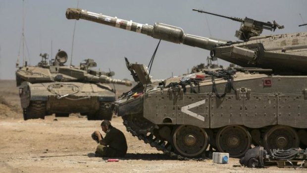 An Israeli soldier sits in the shade next to a tank near the border with Gaza.