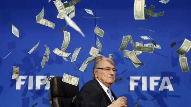 British comedian known as Lee Nelson (unseen) throws banknotes at FIFA President Sepp Blatter as he arrives for a news conference last month.