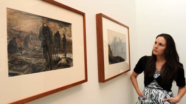 Assistant curator at the Australian War Memorial, Dr. Emma Kindred, with two paintings by WWII official war artist, Alan Moore at an exhibition on show in the WWII galleries. The two images portray activities at the Bergen-Belsen concentration camp, Germany on the day of its liberation.