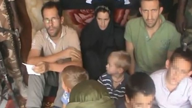 A picture grabbed on a video released by on You Tube on February 25, 2013 shows Tanguy Moulin-Fournier (L) sitting next to his wife, Albane (C, wearing a black veil), his brother Cyril, and their four children flanked by an armed man in an undisclosed place.