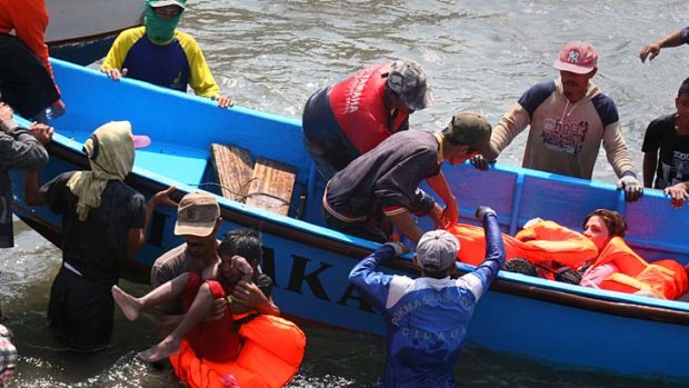 Rescuers assist survivors arriving on fishing boat at the wharf of Cidaun, West Java on July 24, 2013 after an Australia-bound boat carrying asylum-seekers sank off the Indonesian coast.