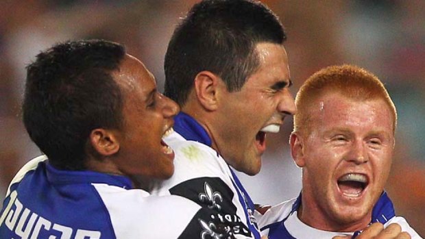 Ben Barba, Bryson Goodwin and Kris Keating of the Bulldogs celebrate scoring a try against the Tigers.