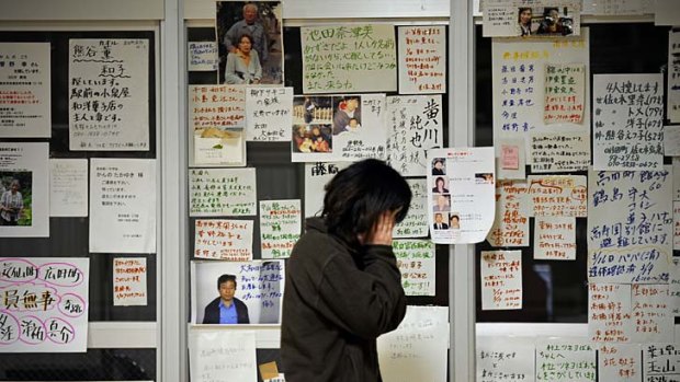 A survivor next to a message board in Rikuzentakata.