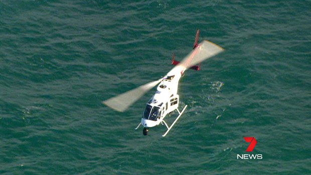 A helicopter searches the waters of Kurrawa Beach yesterday afternoon.