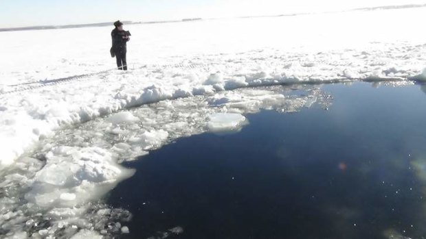 A Russian policeman works near an ice hole, said by the Interior Ministry department for Chelyabinsk region to be the point of impact of the meteor.