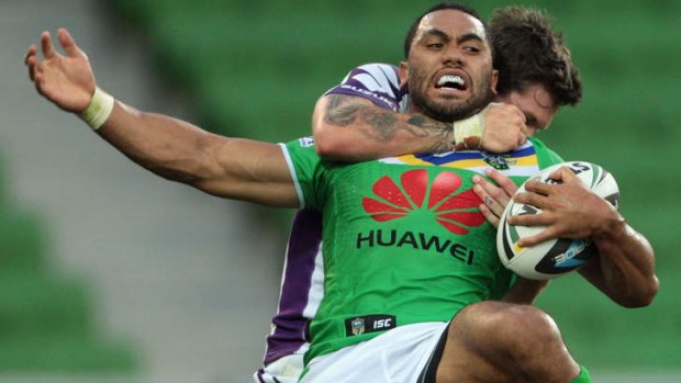 Caught: Canberra's Bill Tupou is held by Ben Hampton.