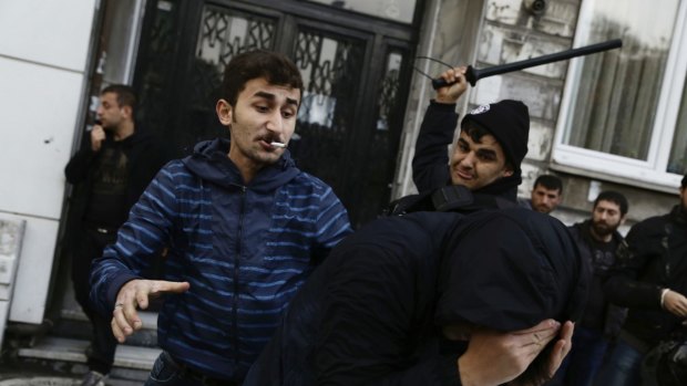 A civilian, left, and a security officer beat a protester demanding freedom for opposition MPs in Istanbul.