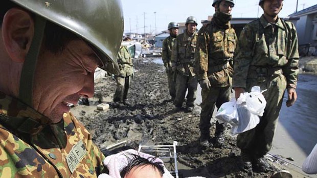 A little ball of hope ... a four-month-old baby girl is carried to safety in Ishimaki by the Japanese Self Defence Force.
