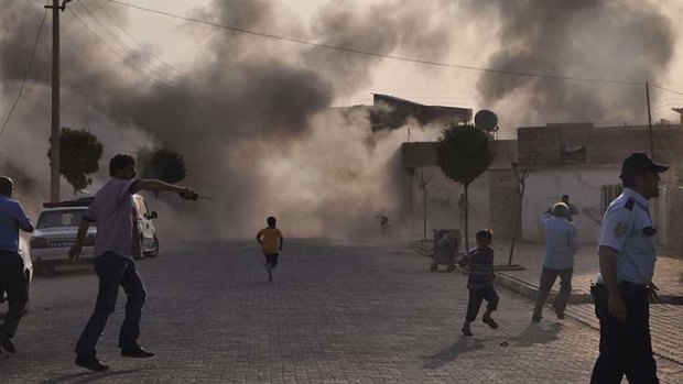 Cross-border attack ... residents of Akcakale, southern Turkey, scramble for safety after a mortar strike fills its streets with smoke.