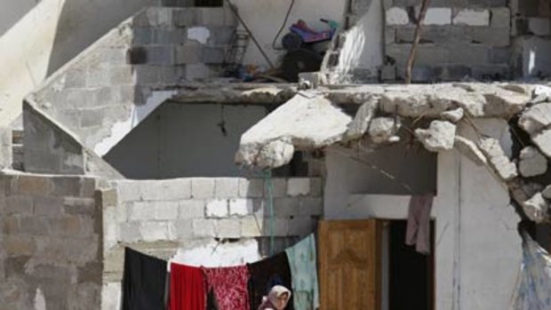 A Palestinian woman hangs laundry next to a a destroyed house in Jebaliya, northern Gaza Strip.
