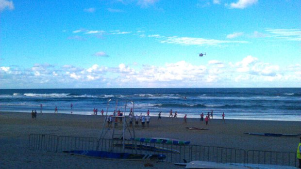 People stand on the beach watching the surf life savers search for a missing teenage competitor.