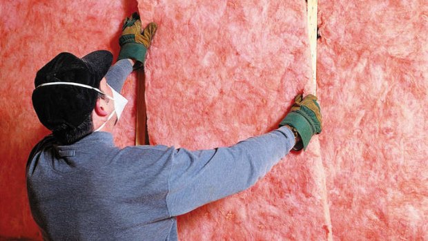 Builder in mask putting in pink batts for insulation.