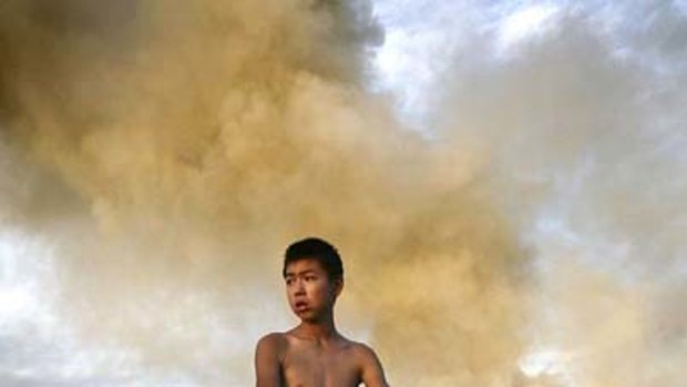 At the crossroads: A boy cycles past a burning waste dump in Changchun, north-east China.