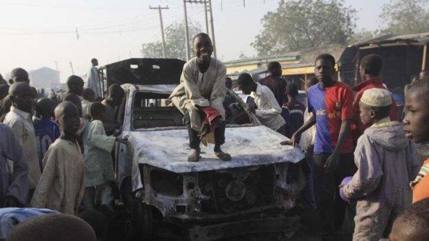 A child stands on a burnt-out police truck in Kano, Nigeria.