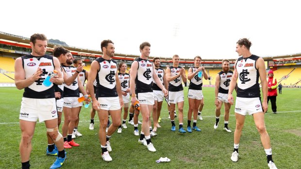 Andrejs Everitt of Carlton (R) is applauded off the field by teammates after playing his 100th game.