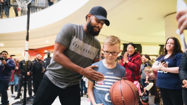 Patty Mills at Belconnen for a book signing for his new book <i>Game Day</i>. Mills congratulates Logan Harrison after Logan beat Mills in a shootout.