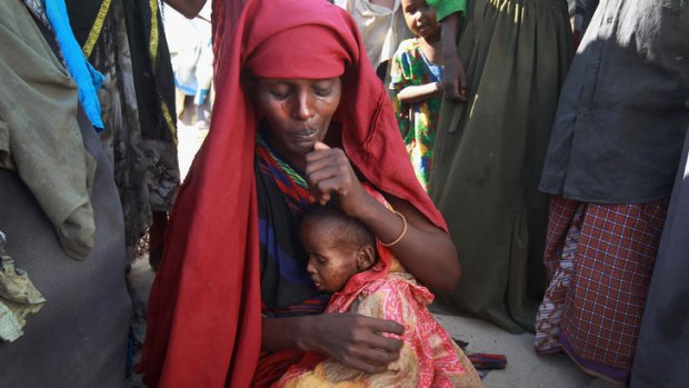 A Somali mother holds her sick child as she waits for food.