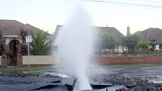 Rubble litters the street as the burst main jets thousands of litres into a residents gardens.