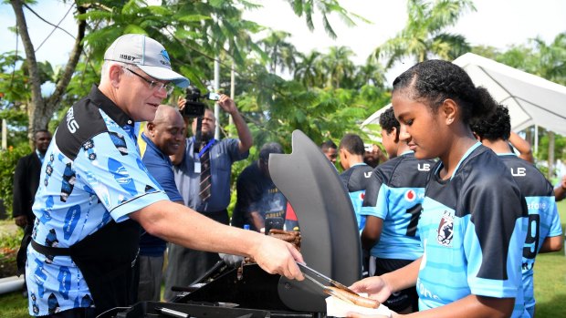 Scott Morrison serves sausages to young rugby league players in Fiji.