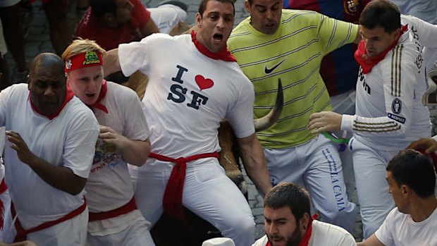 A bull catches up with a runner in Pamplona.