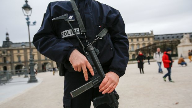 A police officer stands guard holding a gun at the Louvre museum in Paris, France, on Saturday.