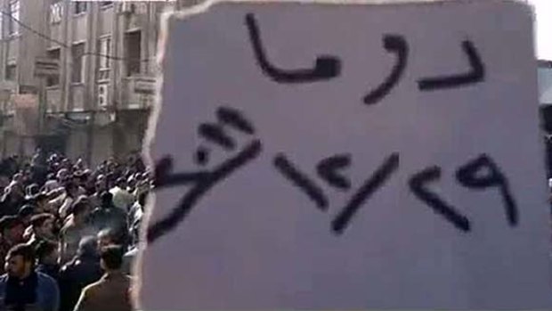 A protester holds a sign during a mass demonstration near Damascus.