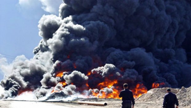 Vulnerable lifeblood ... policemen walk beside a burning pipeline north of Baghdad.  Jihadist websites have  stepped up threats to strike at the oil industry.