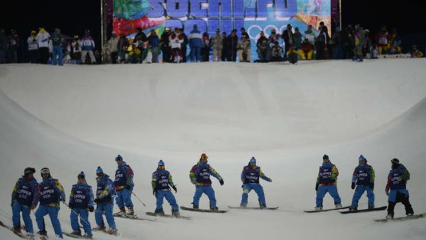 Volunteers inspect the condition of the halfpipe before competitors commence practice sessions.