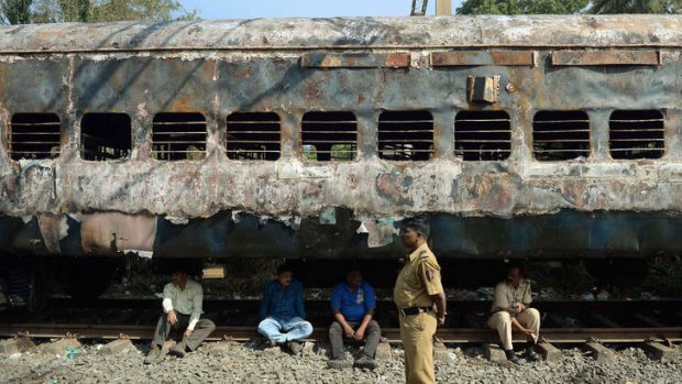 After the fire: Indian railway officials sit beneath a burnt-out carriage.