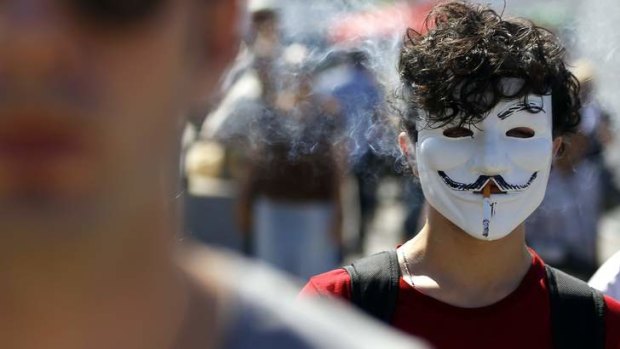 A protester wearing a Guy Fawkes mask smokes while standing in a protest in Istanbul.