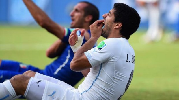 Luis Suarez of Uruguay checks his teeth after biting Italian defender Giorgio Chiellini's shoulder during the World Cup in Brazil.