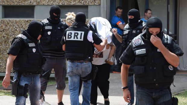 Special forces of France's BRI escort an unidentified woman and a child as they leave the building housing the apartment of a man suspected of carrying out an attack in Saint-Priest near Lyon.