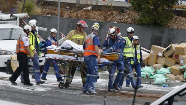 Rescue workers carry away one of the people trapped under the truck.