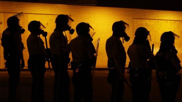 Police wait to advance on demonstrators after tear-gas was used to disperse a crowd on Sunday night in Ferguson, Missouri.