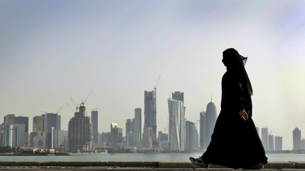 A woman walks in front of the city skyline in Doha, Qatar. 