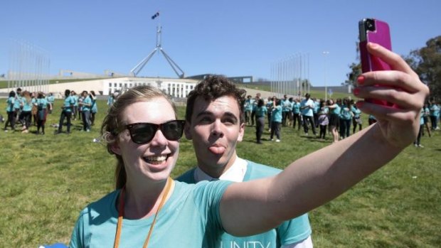 Liz Rhodes takes a selfie of her and Darcy Lower as 350 young people get into formation to spell out their anti-poverty message.