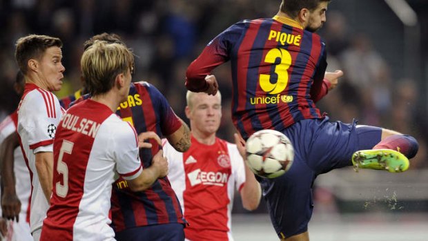 Barcelona's Gerard Pique gets to the ball ahead of Christian Poulsen of Ajax.
